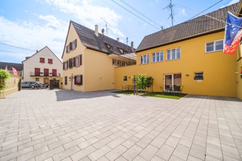 Les Ambrades courtyard in Sigolsheim with colorful traditional buildings and paved patio area