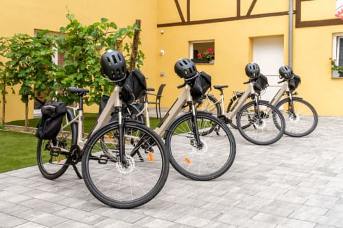 Five electric bikes with helmets lined up at Les Ambrades cottage in Kaysersberg, France