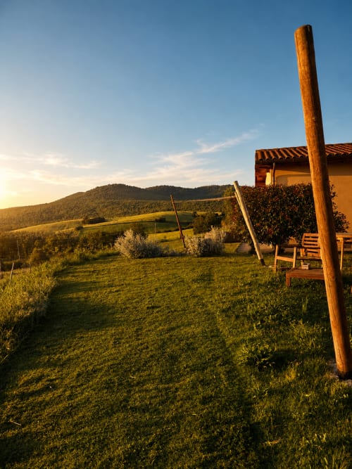 Vista del tramonto sulla campagna toscana dalla terrazza di Il Poggio di Musignano con dolci colline e pergolato in legno