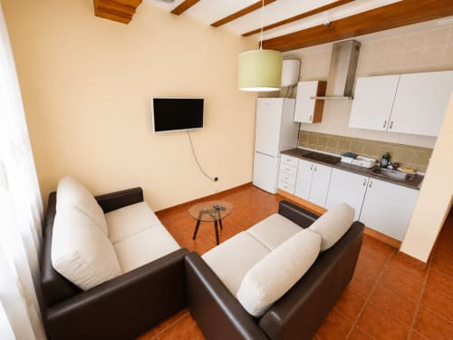 Moderna cocina de estudio y sala de estar en la villa Finca El Arroyo de Alcaraz con sofá de cuero y TV colgada