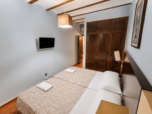 Moderno dormitorio en villa Finca El Arroyo de Alcaraz con cama, TV de pantalla plana, armario de madera y vigas vistas