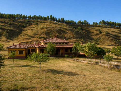 Villa Finca El Arroyo en Alcaraz con tejado de barro, muros amarillos, jardines paisajísticos y bosques en las laderas