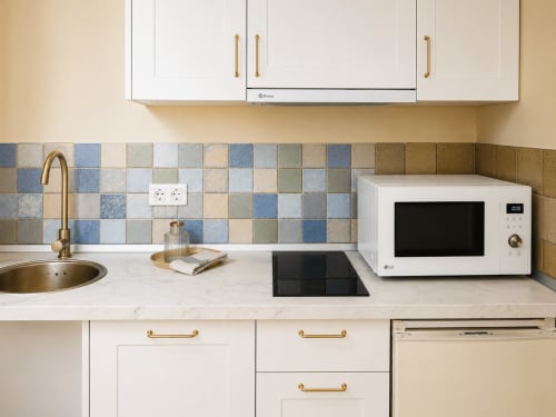Cocina moderna en el apartamento Holibai Misiño, Baiona. Muebles blancos, encimera de mármol, azulejos azules y microondas LG.