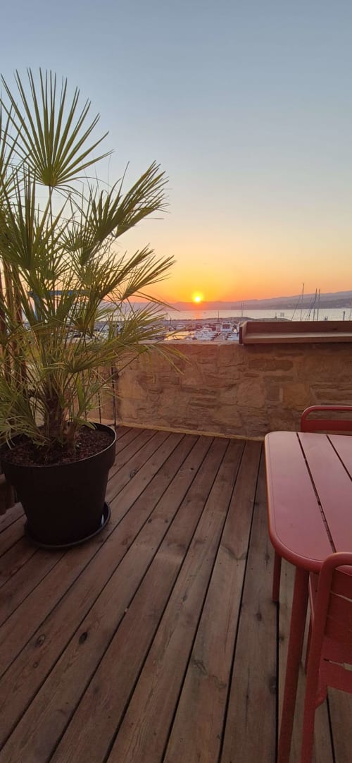 Vue du coucher de soleil depuis la terrasse des Lecques à Saint-Cyr-sur-Mer avec palmier et bateaux du port