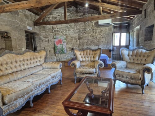 Elegante sala de estar con muros de piedra, muebles vintage y vigas de madera en Aldea Rural Pazos De Arenteiro