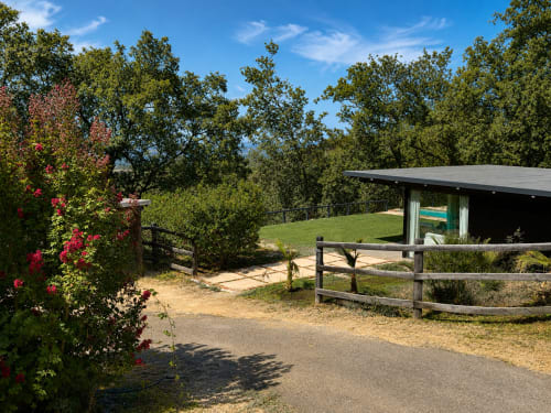 Refugio rústico con cerca de madera y flores rosas con vistas a prados verdes en El Escondite De Pedro Malillo, Candeleda