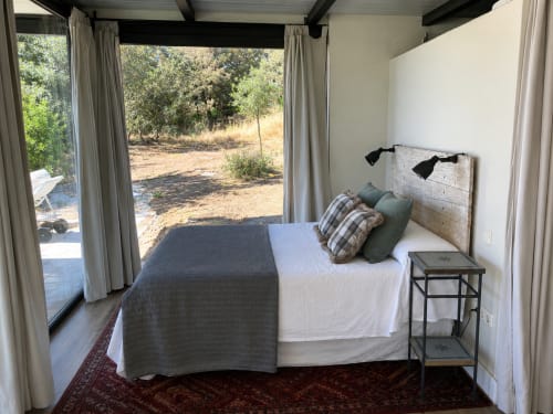 Dormitorio rústico con cabecera de madera blanqueada, almohadas a cuadros y vistas al campo en El Escondite De Pedro Malillo