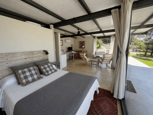 Amplio dormitorio de villa con cama, techo moderno, suelos de madera, zona de estar y terraza en El Escondite De Pedro Malillo
