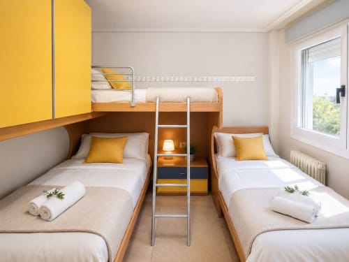 Dormitorio compartido moderno en el hotel Holibai de Baiona con cama litera, dos camas individuales, detalles amarillos y amplia ventana