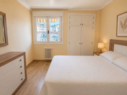 Dormitorio luminoso y espacioso del hotel Holibai en Baiona con cama doble, muebles de madera y vistas a la ciudad