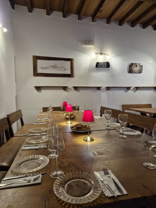 Elegante comedor en Aldea Rural Pazos De Arenteiro con vigas de madera, mesa dispuesta con copas de cristal y detalles rosa
