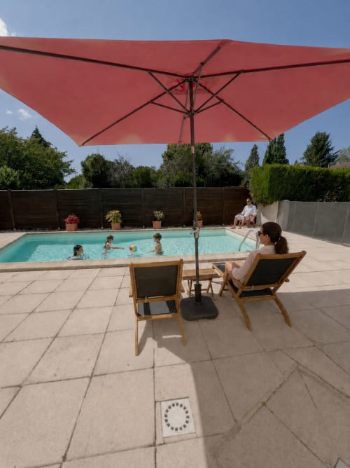 Famille profitant de la piscine du gîte Le Clos Bussy à Bellerive-sur-Allier sous un parasol rouge