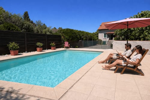 Couple se relaxant près de la piscine turquoise du gîte Le Clos Bussy à Bellerive-sur-Allier avec parasol et transats