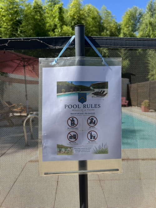 Panneau de règles de piscine au gîte Le Clos Bussy à Bellerive-sur-Allier, affichant les directives et restrictions du bassin naturel en sel.