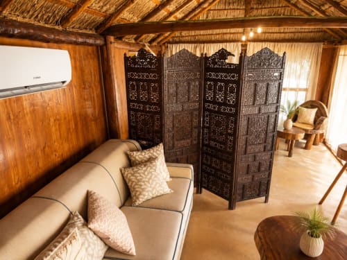 Cozy Isla Mujeres cottage interior with beige sofa, ornate room divider, wooden ceiling, and garden view access