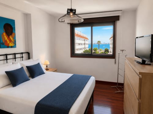 Dormitorio moderno del hotel Holibai en Baiona con vistas al mar, acentos azules y mobiliario contemporáneo
