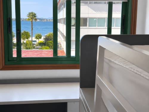 Vista costera de Baiona desde la habitación del hotel Holibai con ventanas de marco verde hacia el mar Mediterráneo