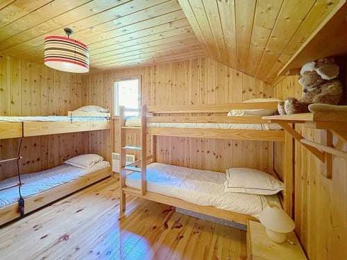Dortoir de chalet en bois avec lits superposés et suspension rayée, hébergement familial à la station de ski de Montgenèvre