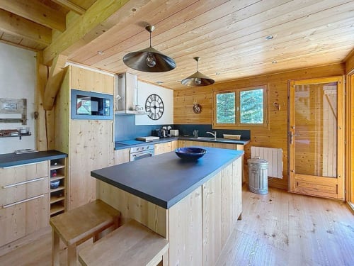 Cuisine moderne en bois du chalet de Montgenèvre avec îlot, électroménagers inox et plafond à poutres