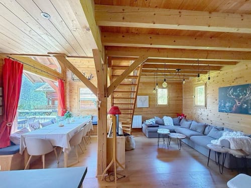 Intérieur spacieux d'un chalet en bois avec salle à manger, salon et vue sur les montagnes à Montgenèvre