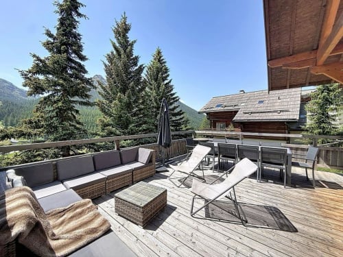 Terrasse spacieuse du chalet Les Tanières de Montgenèvre avec salon, transats et vue sur les montagnes