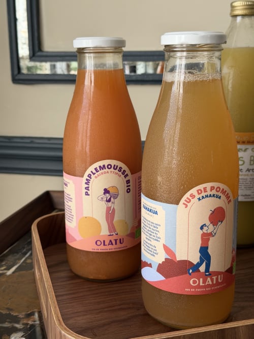 Deux bouteilles de jus français coloré avec étiquettes sur plateau en bois à la maison d'hôtes L'ODE A PIERRE à Dax