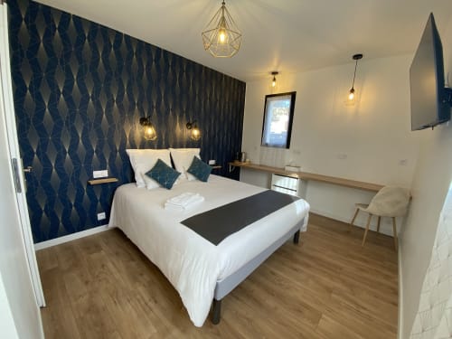 Chambre moderne à La Maison Blanche B&B à Bouguenais avec lit blanc, mur à motifs marine et luminaires suspendus