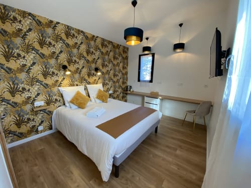 Chambre moderne de l'hôtel La Maison Blanche à Bouguenais avec papier peint motifs, lit blanc et luminaires suspendus