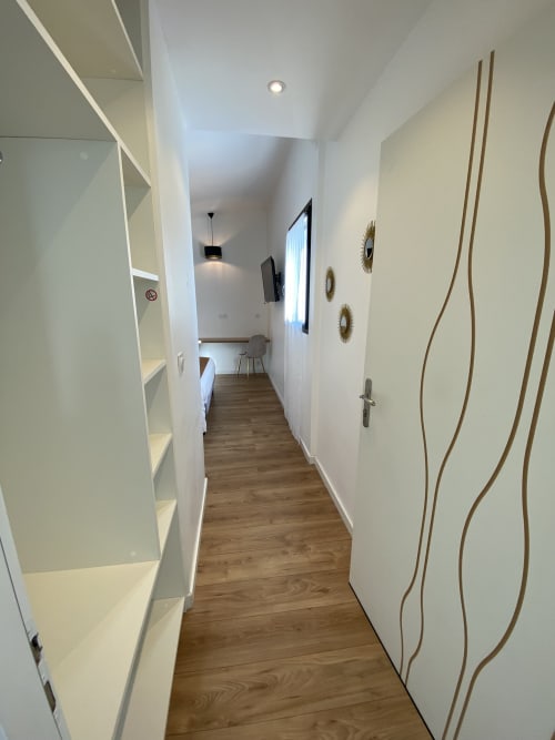 Couloir moderne de La Maison Blanche B&B à Bouguenais avec murs blancs, parquet et éléments décoratifs