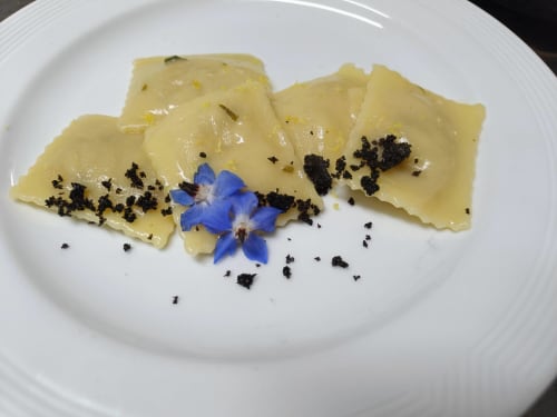 Plated ravioli with black truffle crumble and blue flower garnish at Hotel Ristorante alle Querce, Castelbuono