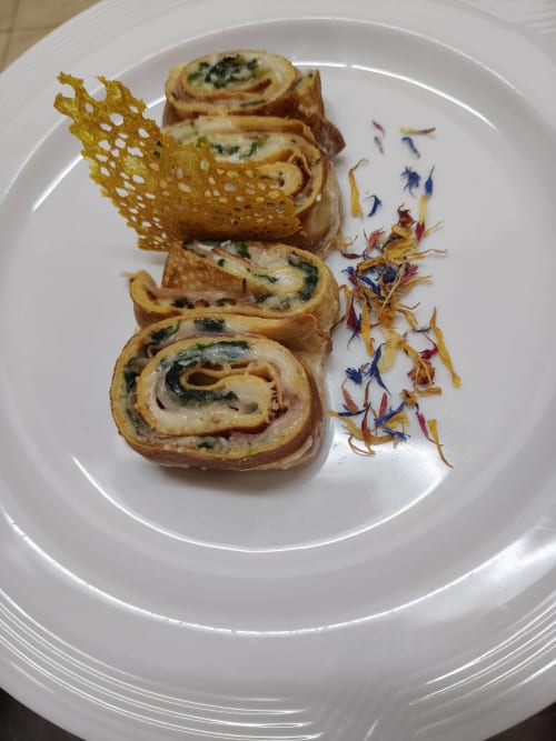 Herb-filled pasta rolls with crispy tuile and edible flowers plated at Hotel Ristorante alle Querce, Castelbuono