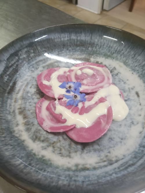 Elegant plated dessert with pink and white swirl frosting and edible blue flowers at Hotel Ristorante alle Querce,