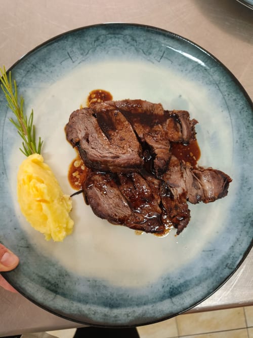 Seared duck breast slices with sauce, mashed potato, and rosemary garnish at Hotel Ristorante alle Querce, Castelbuono