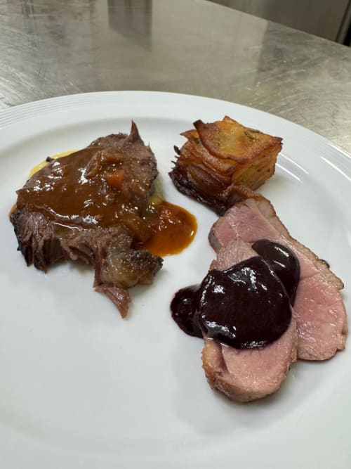 Elegant plated dish at Hotel Ristorante alle Querce featuring braised meat, sliced duck breast with dark sauce, and crispy