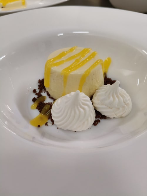 Elegant plated dessert with vanilla panna cotta, yellow citrus sauce, white meringue, and chocolate crumble at Hotel