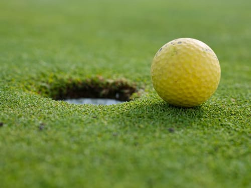 Balle de golf jaune sur le green près du trou au Clos Saint Maurin, Saint Maurin