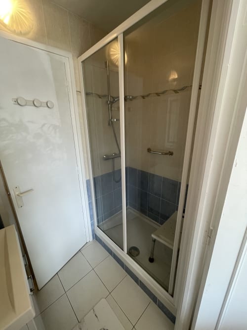 Douche moderne avec portes en verre et accents de carrelage bleu au Studio L'île verte de Parenthèse En Finistère, Guimiliau