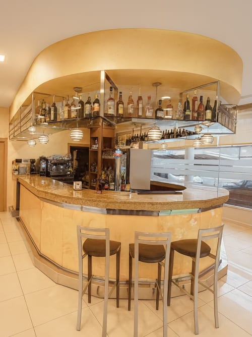 Elegante bar lounge del Hotel Villa de Cacabelos con mostrador curvo, botellas de vino y asientos de barra