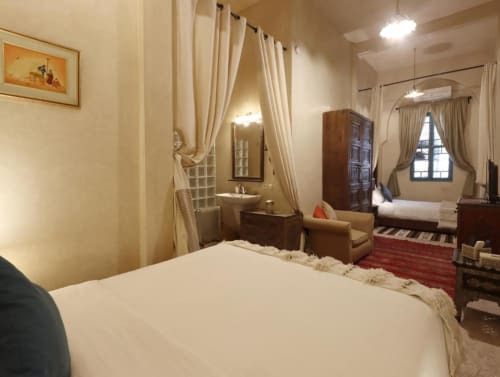 Chambre Triple Supérieure à la Villa El Gada Marrakech avec lit blanc, coin salon, mobilier en bois et salle de bains attenante