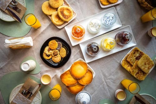 Vue aérienne du petit-déjeuner à la Villa El Gada, Marrakech : viennoiseries, jus frais et confitures sur fond vert