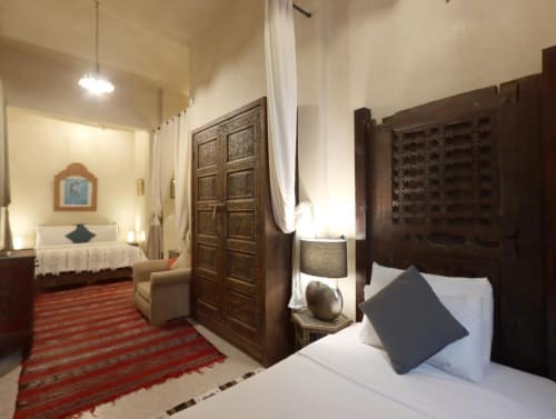 Chambre Triple Supérieure à la Villa El Gada, Marrakech, avec portes en bois sculpté, tapis berbère rouge, literie blanche, bleu foncé