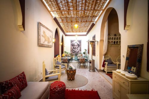 Chambre triple de style marocain à la Villa El Gada à Marrakech avec portes voûtées, plafond décoratif et coussins rouges