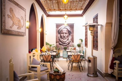 La Suite Triple de la Villa El Gada à Marrakech avec arches marocaines, décoration traditionnelle, coin repas et luminaires suspendus.