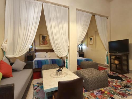 Chambre quadruple à Villa El Gada, Marrakech avec lits à baldaquin, salon, TV écran plat et tapis colorés