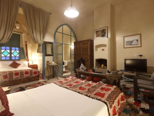 Chambre Quadruple Supérieure à Villa El Gada, Marrakech avec lits jumeaux, cheminée et décoration marocaine traditionnelle