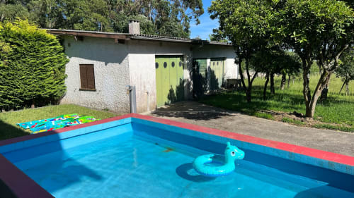 Piscina privada azul-brilhante com brinquedo pato inflável em jardim ensolarado da villa Casa do Sol Norte em Gemeses, Portugal