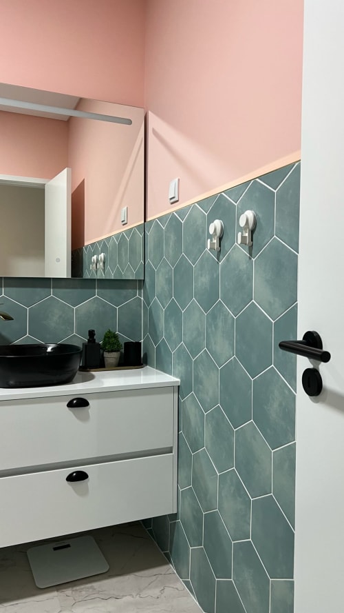 Banheiro moderno da villa Casa do Sol Norte com paredes rosa, azulejos hexagonais verdes, bancada branca e acabamentos pretos