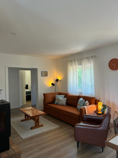 Sala de estar moderna com sofá e poltrona em couro marrom, mesa de centro em madeira e vista para o jardim da villa Casa do Sol Norte