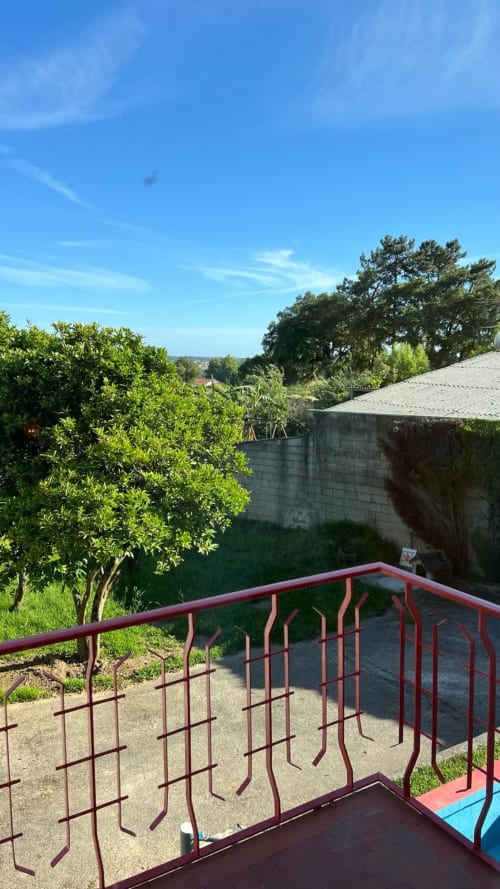 Guarda-corpo vermelho metálico na varanda com vista para jardim arborizado, piscina da villa Casa do Sol Norte em Gemeses