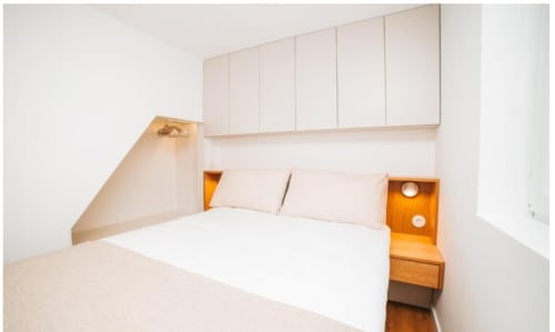 Quarto minimalista da Villa Casa Lobos, Vieira do Minho, com roupa de cama branca, criado de madeira e armazenamento integrado.